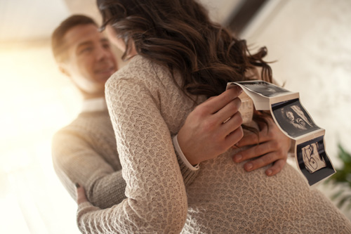 beigewomanandman Pregnant woman and man celebrating with ultrasound