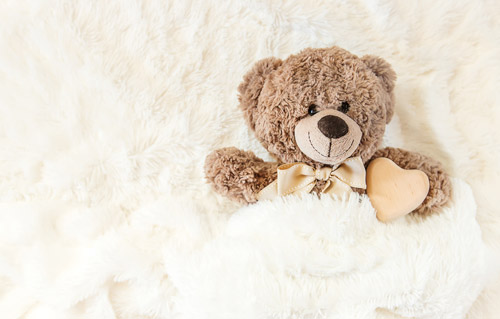 teddy bear wrapped in fluggy blanket