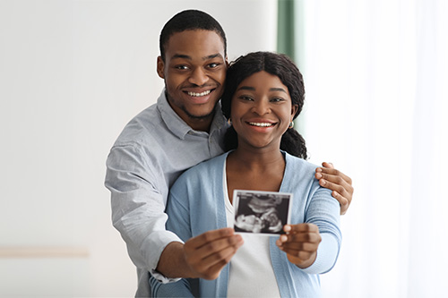 black couple posing with baby sonogram