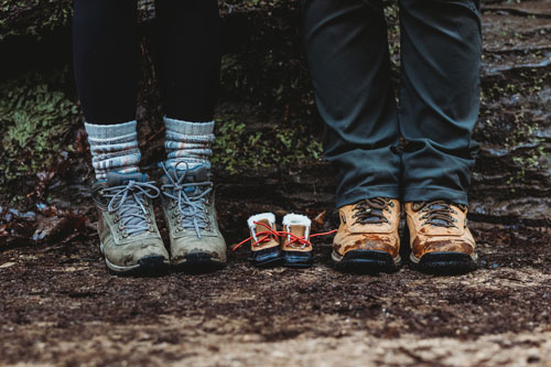 Mom and Dad in hiking boots with baby boots between them